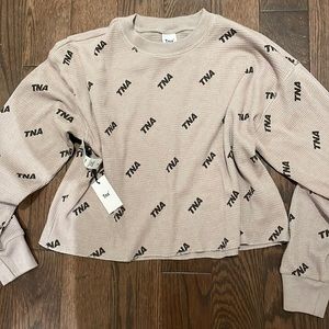 TNA long sleeve logo top. New with tags.  Never worn.
